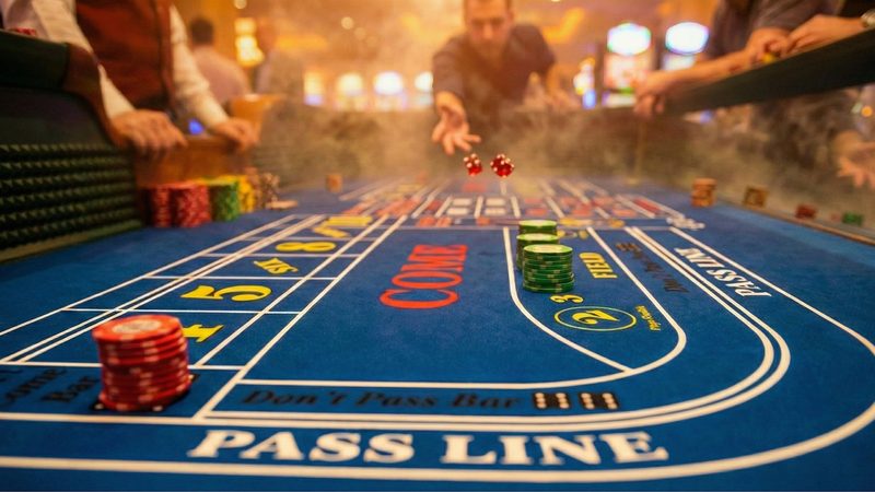 A casino craps table with dice mid-roll over the pass line